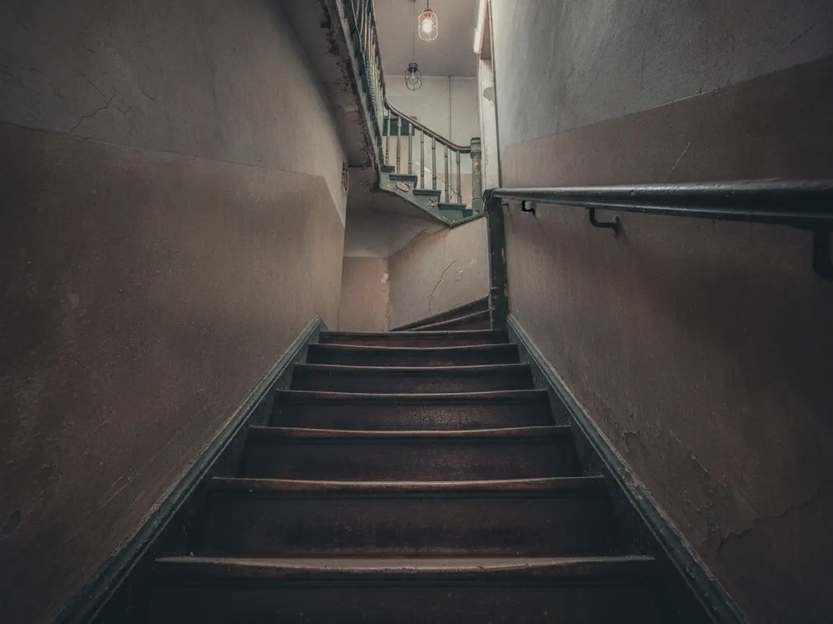 The narrow stairwell of an old tenement walk-up seen from the ground floor.