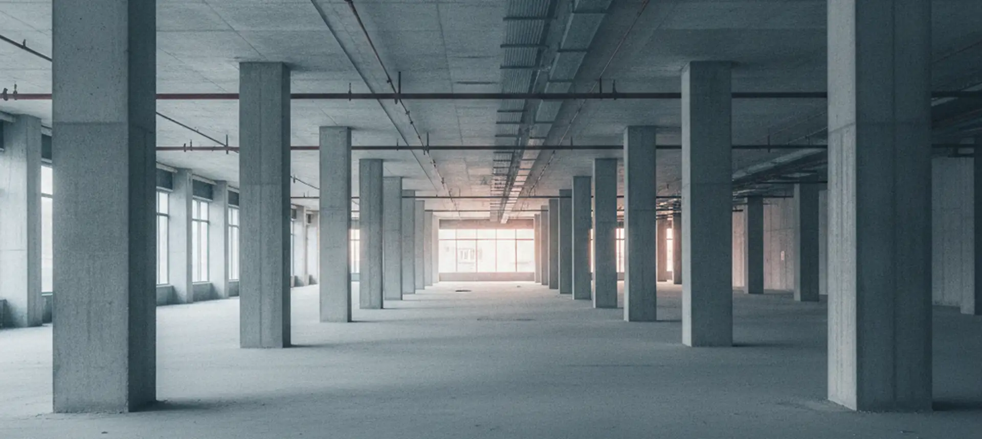 A long stripped commercial floor with structural columns receding into the distance.